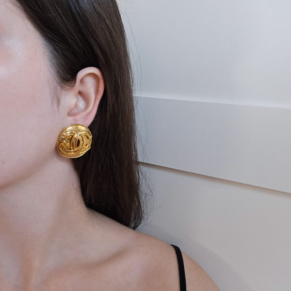 CHANEL - okrągłe złote klipsy vintage z monogramem na modelce
