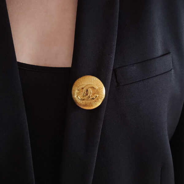 CHANEL - okrągła broszka vintage z logowaniem CC na modelce