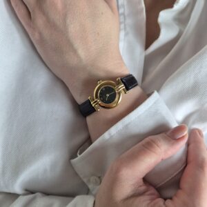 CARTIER - złoty zegarek vintage z ciemną tarczą na modelce