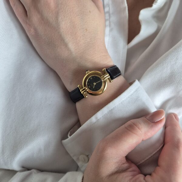 CARTIER - złoty zegarek vintage z ciemną tarczą na modelce