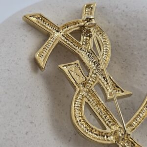 YSL - złota broszka vintage z monogramem zbliżenie na logo
