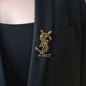 YSL - złota broszka vintage z monogramem na modelce