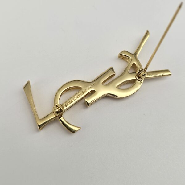 YSL - delikatne złota broszka vintage w kształcie monogramu zbliżenie
