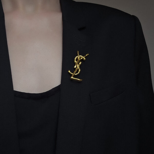 YSL - delikatne złota broszka vintage w kształcie monogramu na sobie