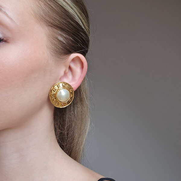 CHANEL - okrągłe klipsy vintage z perłą i wytłaczanym napisem, lata 90. na modelce