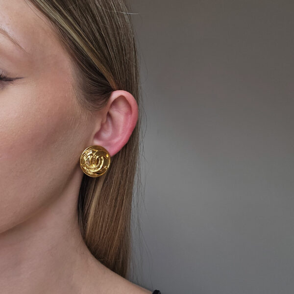 CHANEL - złote klipsy z monogramem na modelce